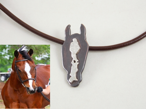 a bay horse (copper metal) with a unique white blaze represented by sterling silver